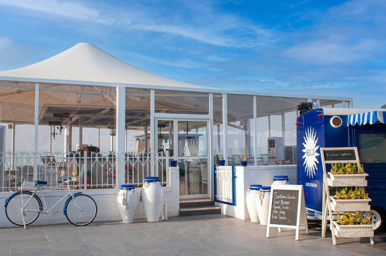 Hotel Hyatt Regency Dubai - Corniche Esterno foto The photo depicts a stylish outdoor dining area with a large white canopy overhead. The structure appears to be predominantly made of glass, allowing natural light to filter in. In front, there are decorative elements such as large white planters and